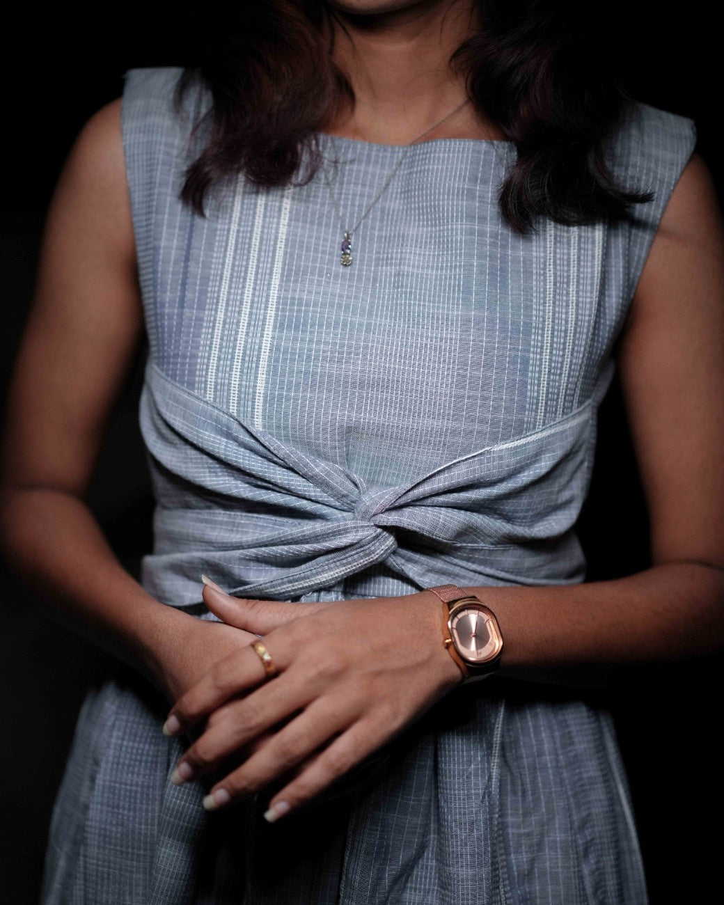Close-up of a woman in a comfortable blue dress with an intricate embroidery design from the Vestures collection, gazing into the distance in a cozy ambiance.