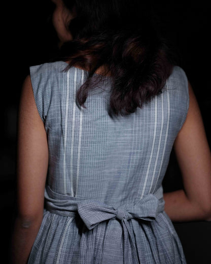 Close-up of the back view of a woman wearing a comfortable blue dress with intricate embroidery design from the Vestures collection, set against a black background.