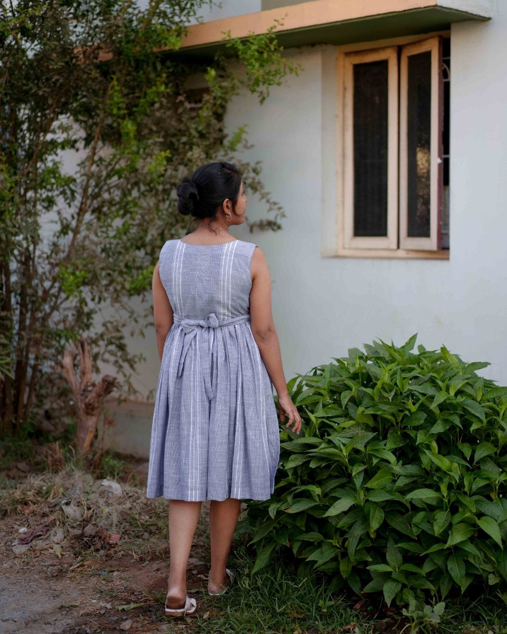 Back view of a woman wearing a comfortable blue dress with intricate embroidery design from the Vestures collection.