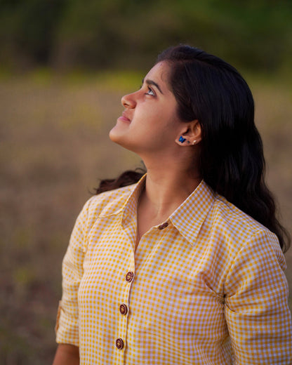 Serene moment as a woman looks up at the sky, wearing a stylish yellow and white checked workwear.