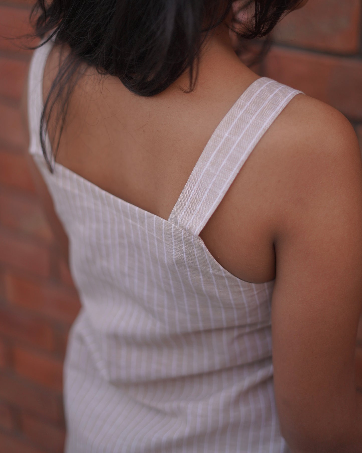 Back right close-up view of the Lacey Pearl Pinafore, focusing on the stylish straps and relaxed yet sophisticated design.