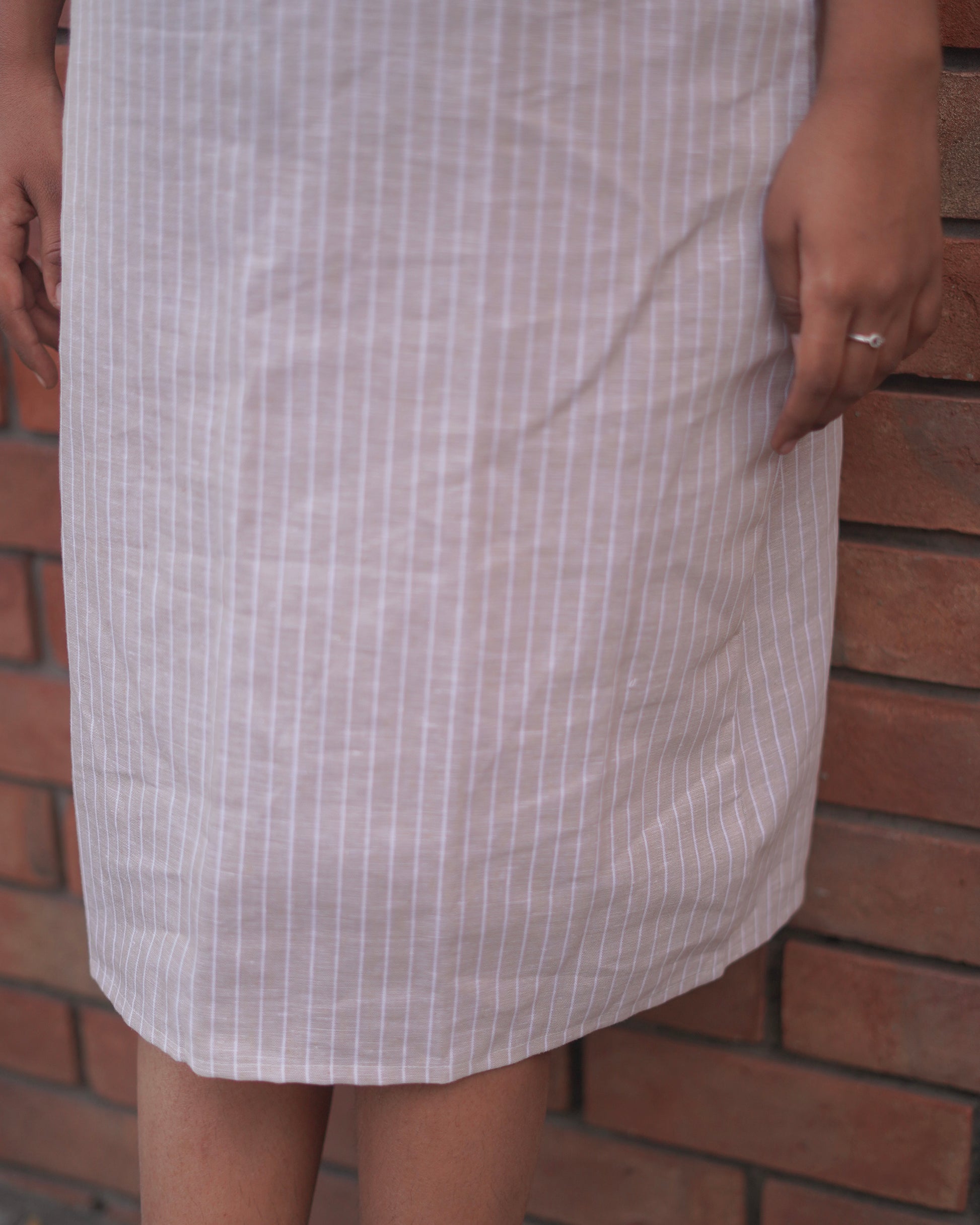 Close-up of the lower half of a Lacey Pearl Pinafore, showcasing the elegant curved hemline and soft, breathable fabric.