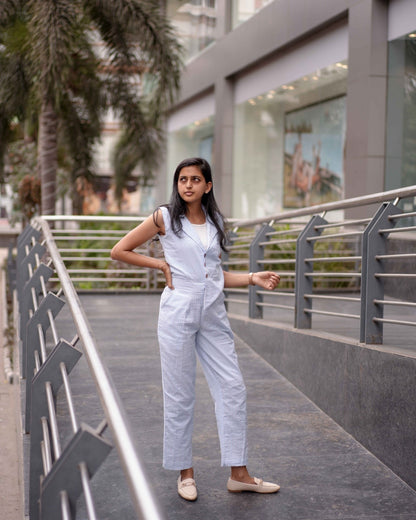 A woman in the Anki Jumpsuit elegantly poses on a lawn pathway, exuding confidence and effortless style.