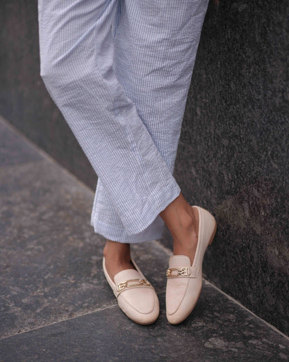 Below-the-knee close-up shot featuring a woman in the Anki Jumpsuit, paired with chic rose gold-cut shoes.