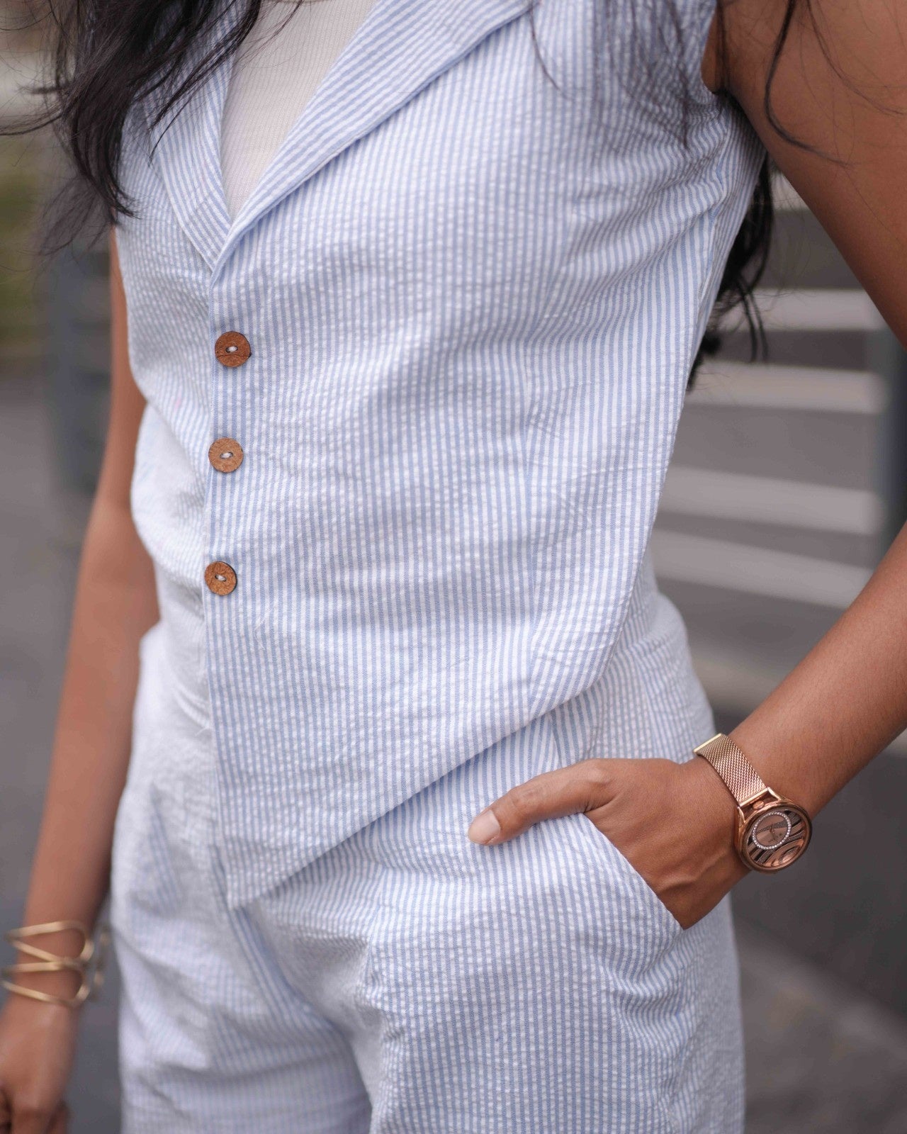 Zoomed-in close-up of a woman wearing a rose gold watch with hands inside pockets, emphasizing the comfort of the Anki Jumpsuit.