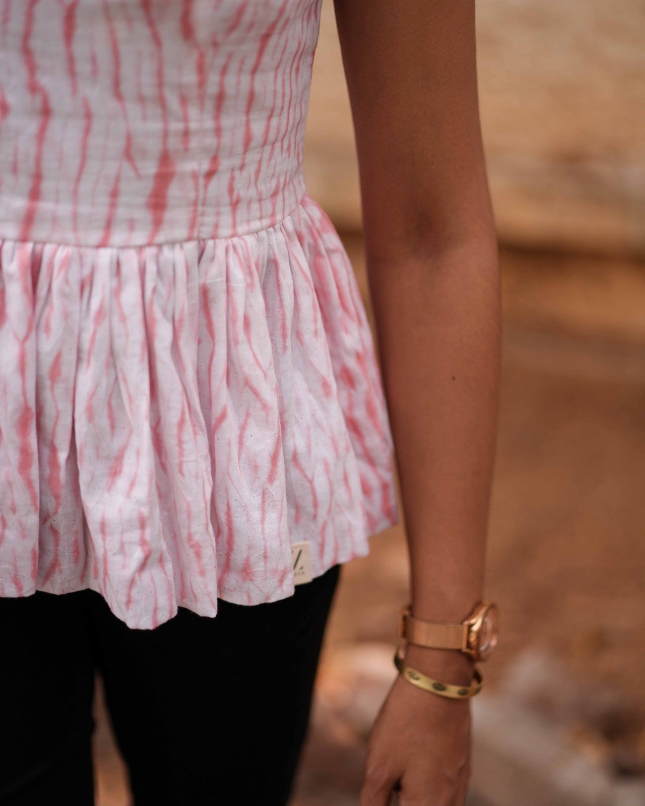 Left-side close-up of the Vil Top, highlighting the soft Mul Mul fabric, stylish torso contrast with pants, and a rose gold watch.
