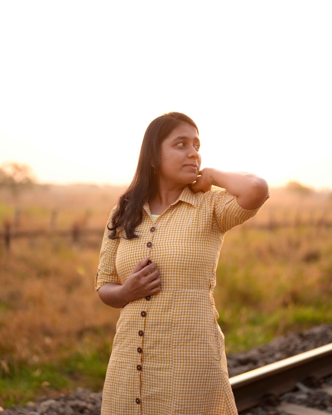 A woman in a comfortable fit Yellow and White Checked Linen Shirt Dress, captured in a close-up front view as she gazes into the distance.